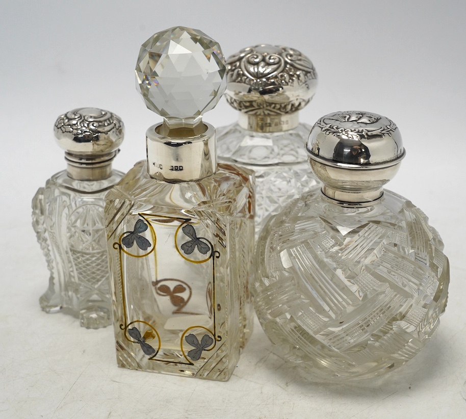 Four assorted early 20th century silver mounted glass scent bottles, tallest 16.1cm. Condition - fair